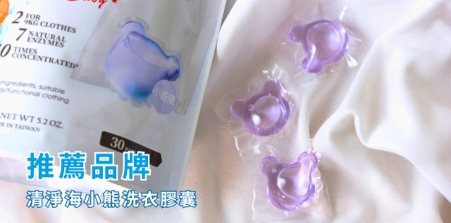 推薦品牌清淨海小熊洗衣膠囊 白色的布上放著清淨海小熊洗衣球的包裝與紫色小熊造型洗衣球