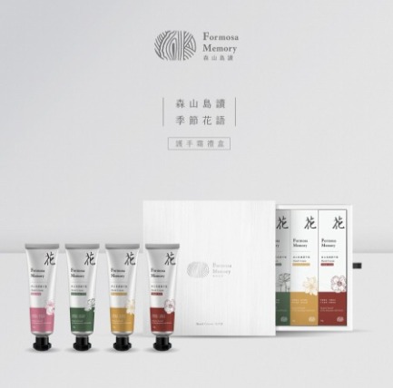 在灰色的背景前放著灰色方形禮盒，禮盒旁放著四隻護手霜，分別是粉色、綠色、黃色以及酒紅色